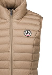Beige gewatteerde mouwloze bodywarmer met voorrits en ronde logo patch met "Just Over The Top JOTT" op de borst.