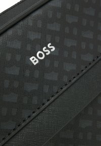 Black textured wallet featuring a patterned surface, accented by a white "BOSS" logo. Includes fine stitching along the edges.