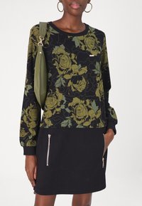 Robe-sweatshirt fleurie avec une base noire ornée de motifs de roses vertes, poches latérales zippées et une silhouette ajustée.