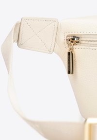 Bílá texturovaná kožená taška se zipovým uzávěrem a zlatým táhlem zipu. Obsahuje čtvercové uchycení popruhu s kontrastním prošitím.