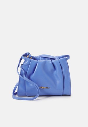 Petit sac bandoulière en cuir bleu avec détail plissé et plaque logo dorée sur le devant sur fond uni.