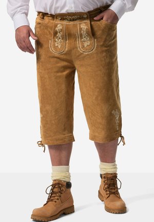Brune ruskinds-shorts med broderet blomsterdesign på lommerne, justerbare manchetter, parret med snørebåndsbrune støvler og cremede sokker.