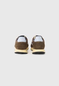 Brown suede athletic shoes with a light blue heel tab, accented by black detailing and a textured rubber sole, featuring the logo on the back.