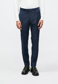 Námornícke nohavice s hladkou textúrou, s rovnou siluetou a skladom vpredu. Nosia sa s čiernymi šľapkami.