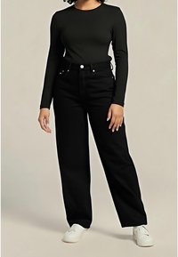 Top nero a maniche lunghe abbinato a pantaloni neri a gamba larga e vita alta e sneakers bianche. Il tessuto ha una texture liscia con dettagli di cucitura minimi.