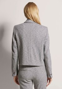 Graue Hahnentritt-Blazer mit taillierter Passform, scharfen Revers und knöpfbaren Manschetten. Aus strukturiertem Stoff und mit cropped Saum.