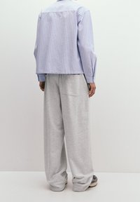 Randig ljusblå skjorta med boxig passform, parat med löst sittande grå mjukisbyxor. Mjuk tyg med en avslappnad silhuett.