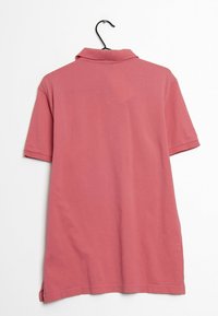 Koszulka polo z krótkim rękawem, z kołnierzykiem, w kolorze różowym, wykonana z miękkiej bawełny. Posiada prosty krój z bocznymi rozcięciami u dołu, co zapewnia dodatkowy komfort.