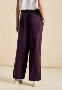 Pantaloni a gamba larga viola realizzati in un tessuto leggero, con una vita elastica e due tasche posteriori, caratterizzati da una texture liscia.