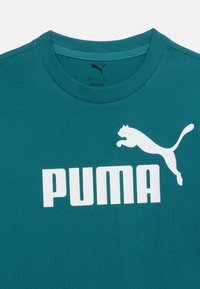 Πράσινο μπλουζάκι με στρογγυλή λαιμόκοψη και λευκό κείμενο "PUMA" μαζί με λογότυπο που δείχνει ένα άλμα πάνθηρα στο στήθος, μέγεθος μεσαίο για ηλικίες 11-12 ετών.