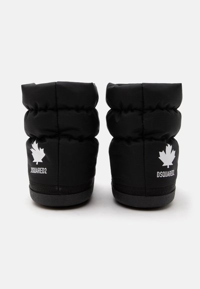 Paire de bottes d'hiver noires matelassées avec semelles épaisses, ornées de logos blancs en forme de feuille d'érable et du texte "DSQUARED2" à l'arrière de chaque botte.