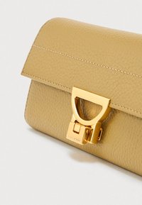 Beige υφασμάτινη δερμάτινη τσάντα φάκελος με λαμπερό χρυσό ορθογώνιο κούμπωμα σε λευκό φόντο.