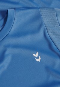 T-shirt de sport bleu en tissu lisse et léger. Présente un col rond et un panneau en mesh sur l'épaule, orné d'un logo blanc.