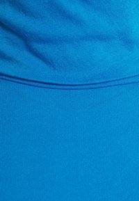 Sininen ribbed-kangas, joka näyttää sileältä ja sopivan muotoilun omaavalta, ja alaosan lähellä näkyy sauman yksityiskohta.