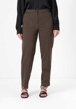 Brown patterned trousers with a slim fit, featuring a subtle geometric design. Paired with black strappy sandals and a loose black blouse.