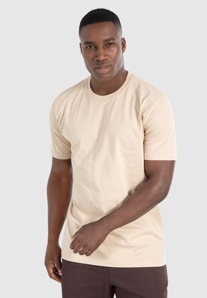 Beige cotton t-shirt with a round neck, short sleeves, and a fitted design. Smooth texture, no visible patterns or accents.