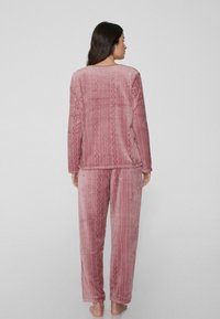 Weiches, strukturiertes pinkes Pyjama-Set mit einem locker sitzenden Langarmoberteil und passenden Hosen mit einem dezenten geometrischen Muster.