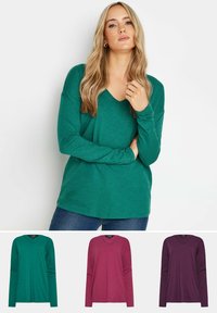 Grön långärmad V-ringad skjorta med avslappnad passform och mjuk textur. Ytterligare färger inkluderar vinröd och mörklila, som visas nedan.