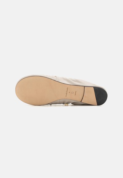 Scarpa beige morbida con tomaia testurizzata e suola in gomma liscia color pelle. Presenta un leggero tacco e una minimalistica marcatura sulla suola.