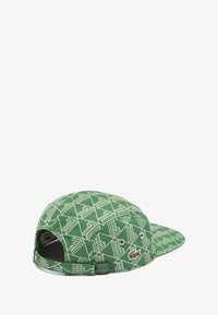 Cappello verde con un motivo geometrico in verde più chiaro, dotato di occhielli per la ventilazione e una patch con il logo Lacoste sul lato.