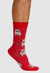 Rote Socken mit einem verspielten Muster aus Cartoon-Hunden und Lebkuchenfiguren. Hergestellt aus einem weichen, dehnbaren Material mit glatter Textur.