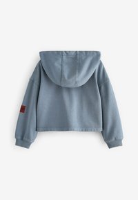 Cropped felpa blu in tessuto morbido, con cappuccio, polsini a costine e una finitura testurizzata con un piccolo etichetta rossa sulla manica.