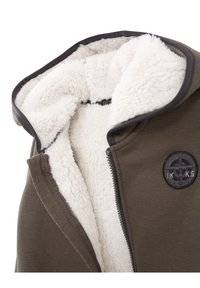 Olivgrüne Zip-Jacke mit weißem Fleece-Futter, großer Kapuze und schwarzem, rundem Logodetail auf der Brust. Mit glattem Außenmaterial.
