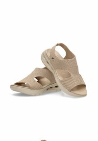 Sandalias beige con textura de punto, punta abierta y correa en el tobillo. Presentan una suela acolchada y cortes diagonales para mayor transpirabilidad.