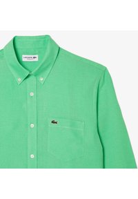 Camicia button-up verde chiaro con taschino frontale decorato con un piccolo logo di coccodrillo ricamato e colletto button-down.