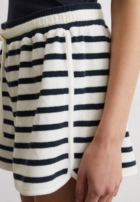 Gestreepte shorts van zacht, badstofmateriaal. Kenmerkt afwisselend witte en marineblauwe strepen, een elastische tailleband en zijzakken.