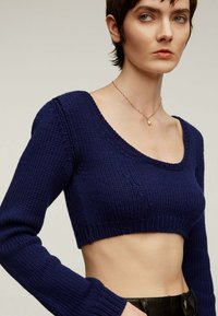 Suéter corto azul marino hecho de un tejido de punto texturizado, con un escote en forma de barco amplio y mangas largas, que cuenta con puños y dobladillo acanalados.