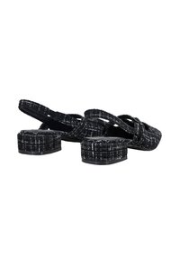 Sandales texturées noir et blanc avec un talon carré, dos ouvert et sangles croisées, arborant un subtil motif tartan.