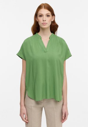 Blusa verde a maniche corte con scollatura a V, realizzata in tessuto leggero. Presenta spacchi laterali e una vestibilità fluida e rilassata.