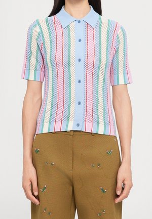 Chemise en maille à manches courtes avec boutons, rayures verticales pastel et motif semblable au crochet, associée à un pantalon marron brodé de petites fleurs.