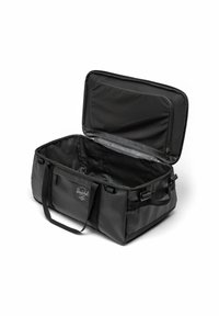 Sac de sport noir en matériau durable, doté d'un intérieur spacieux, de doubles poignées, d'une fermeture éclair et d'un écusson de marque sur le côté.