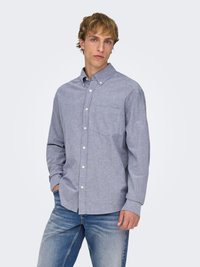 Lichtblauw overhemd met knopen, een kraag, een borstzak en een gestructureerde stof, gecombineerd met vervaagde blauwe jeans.