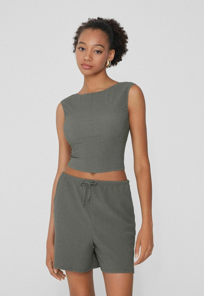 Ensemble en deux pièces gris à côtes comprenant un crop top ajusté avec un col rond et un short avec cordon de serrage élastique, le tout fabriqué à partir d'un matériau léger.
