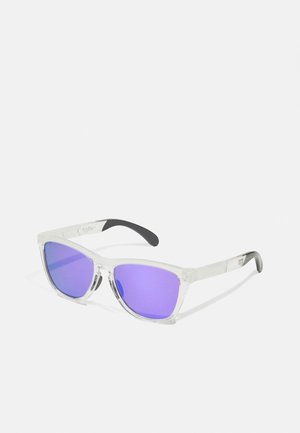 Klare Plastiksonnenbrille mit lila getönten Gläsern, eckiger Form, strukturierten schwarzen Gummibügelspitzen und minimaler Markenwerbung am Bügel.