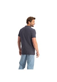 Donkergrijze polo met een kraag, korte mouwen en een relaxed fit, gecombineerd met lichtblauwe jeans. Toont de achterkant en minimale details.