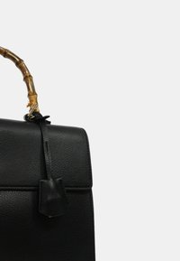 Borsa a tracolla in pelle nera con un design strutturato, manico in bambù e chiusura piatta. Presenta una pelle testurizzata e hardware minimal.