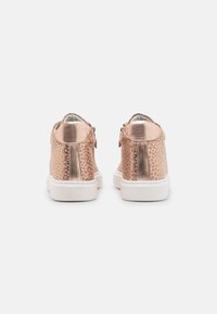 Roségoldene Sneakers mit einem strukturierten, Schlangenledermuster, metallischen Akzenten und weißen Gummisohlen. Die Rückansicht zeigt einen abgerundeten Kragen und Schnürsenkel.