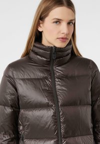 Bruine pufferjas met een hoge kraag en een ritssluiting aan de voorkant. Bevat gestikte delen voor isolatie en een gladde, glanzende textuur.