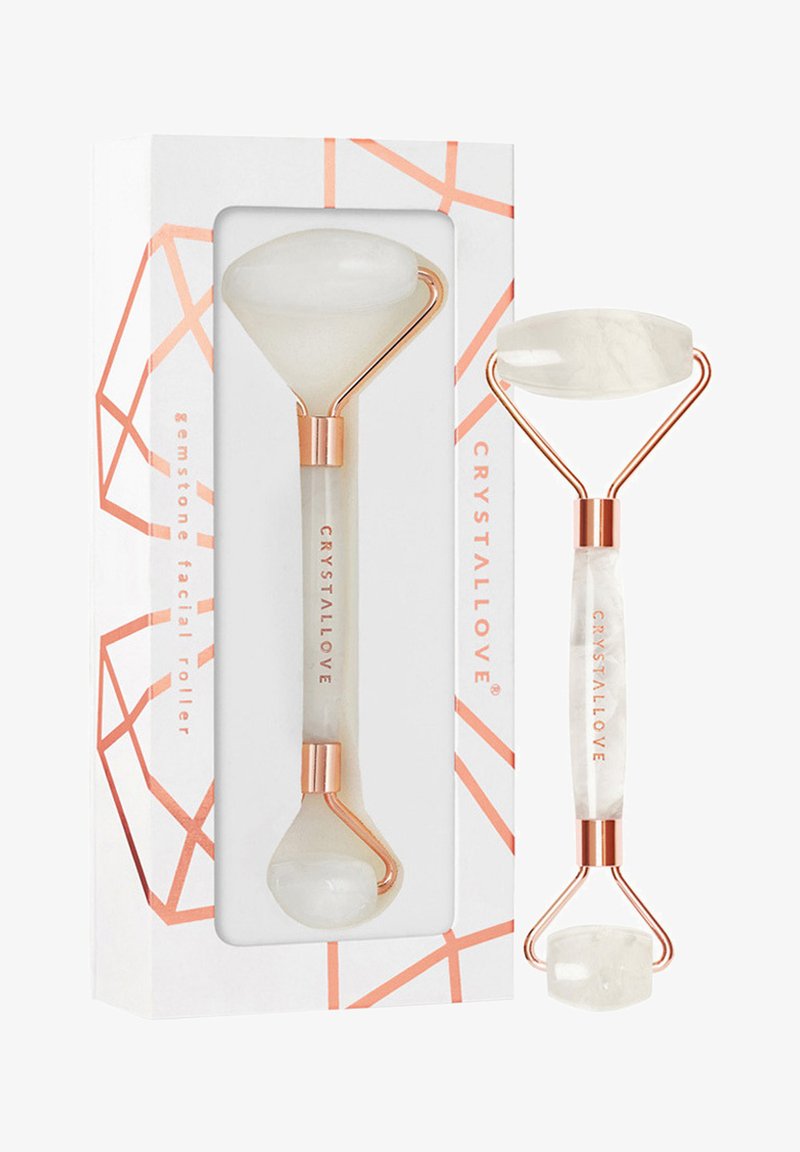 Rullo facciale in pietra preziosa con estremità in giada bianca e telaio in metallo oro rosa. Imballato in una scatola con motivo geometrico e branding.