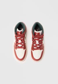 Czerwono-białe sneakersy typu high-top wykonane z materiałów skórzanych i siateczkowych, z perforowanym czubkiem, sznurówkami oraz czarnym logo po boku.
