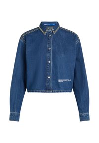Camicia in denim cropped di colore blu scuro con borchie argentate lungo il colletto. Presenta una chiusura a bottoni e un logo bianco sulla parte anteriore sinistra in corrispondenza della vita.
