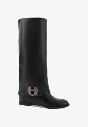 Bota de cuero negro hasta la rodilla con una textura suave, punta redonda, suela plana y un acento de logo plateado en el tobillo.