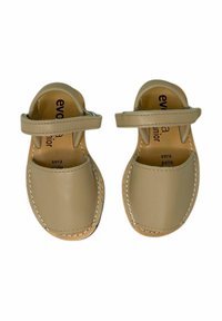 Sandali in pelle beige chiaro con una fascia sulla parte superiore, punta arrotondata e cuciture bianche. Texture morbida e design minimalista.