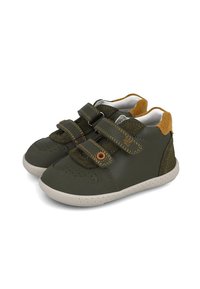 Zapatillas verdes con dos tiras de Velcro, puntera perforada, cuello acolchado y suela de goma. Destacan por detalles en ante marrón y costuras amarillas.
