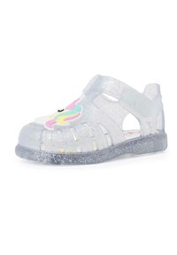 Transparent glitter sandals with a rounded toe, cut-out design, and a colorful unicorn accent on the front. Sparkly sole.
