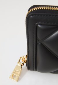 Carteira de pele sintética preta com design acolchoado, zíper e detalhes em dourado, apresentando uma etiqueta com "AMOR" e um corte em formato de coração.